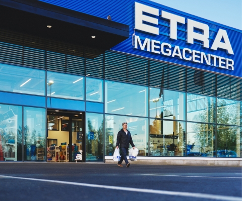Entr&eacute;n till en Etra Megacenter-butik, en kund g&aring;r ut med shoppingkassar.