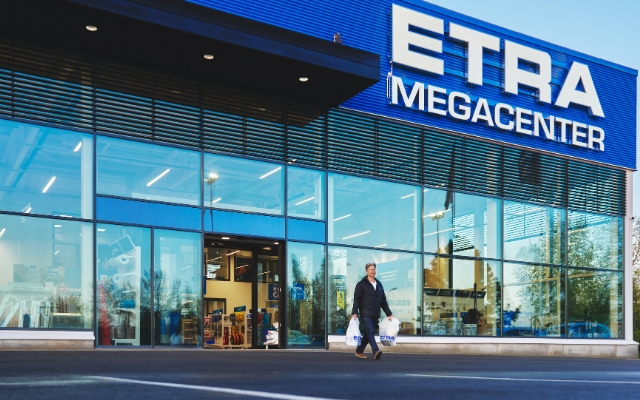 Entr&eacute;n till en Etra Megacenter-butik, en kund g&aring;r ut med shoppingkassar.
