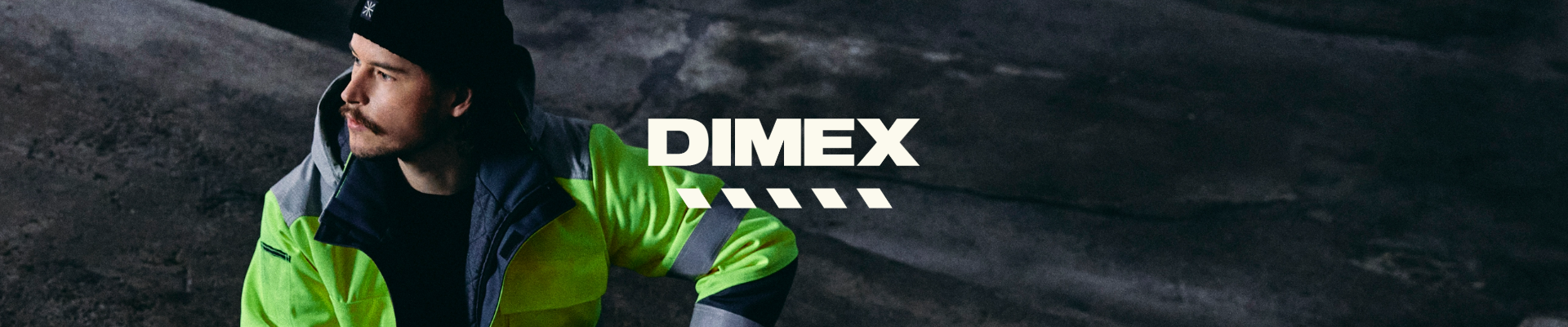 Henkilö istuu kyykyssä hämärässä teollisuusympäristössä pukeutuneena kirkkaan keltaiseen ja harmaaseen heijastavaan työasuun. Kuvan keskellä on valkoinen DIMEX-logo.