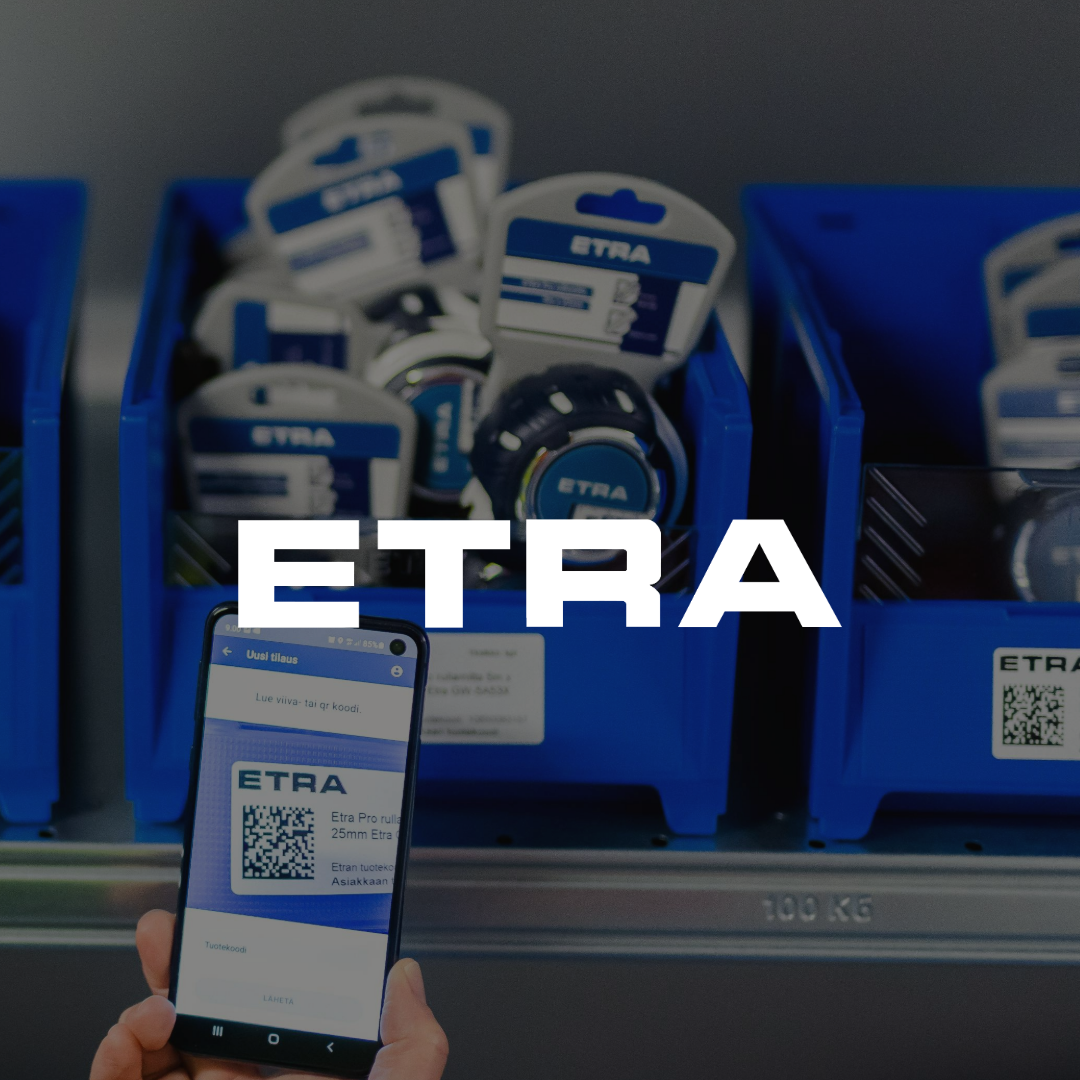Sinisissä muovilaatikoissa on ETRA-merkkisiä tuotteita hyllyllä. Etualalla käsi pitelee älypuhelinta, jonka näytöllä on ETRA-sovellus ja QR-koodi.