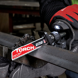Henkilö käyttää Milwaukee TORCH -metallikatkaisuterällä varustettua pistosahaa katkaistakseen paksua metalliputkea. Terän etiketissä lukee "TORCH METAL CUTTING". Käyttäjällä on punaiset turvakäsineet ja musta työtakki.