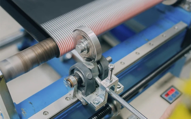 Close-up of a moving roller mechanism with striped material running through it in an industrial setting.