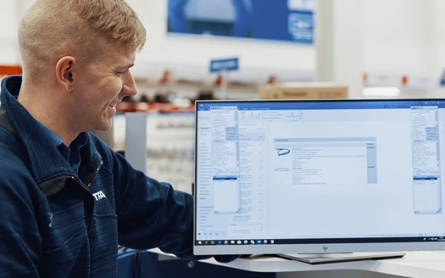 Etra employee viewing product information on a computer screen in a store environment.