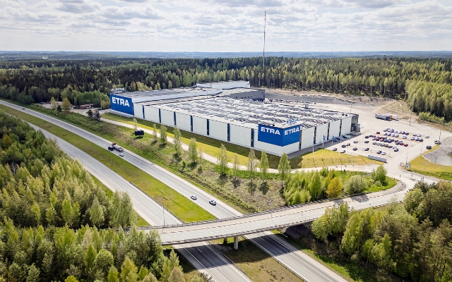 Etran logistiikkakeskuksen ulkokuva &ndash; suuri, moderni varastorakennus, jossa on yrityksen logo n&auml;kyv&auml;sti esill&auml;. Taustalla avoin taivas ja laaja piha-alue.